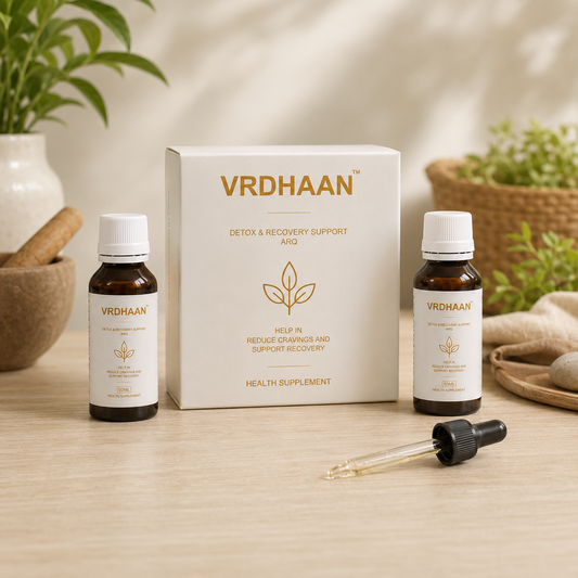 VRDHAAN Detox & Recovery Support AGo health supplement set, featuring a white product box, two amber glass dropper bottles with white labels, and a glass pipette on a light wooden table with a soft, warm background.